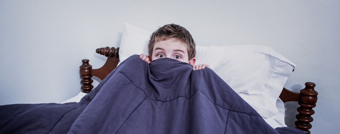 Child pulling covers up over lower face and looking scared